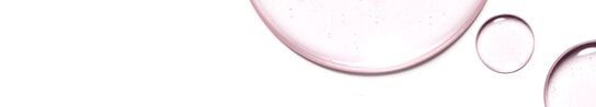 A close up of light pink liquid with speckles on a white background