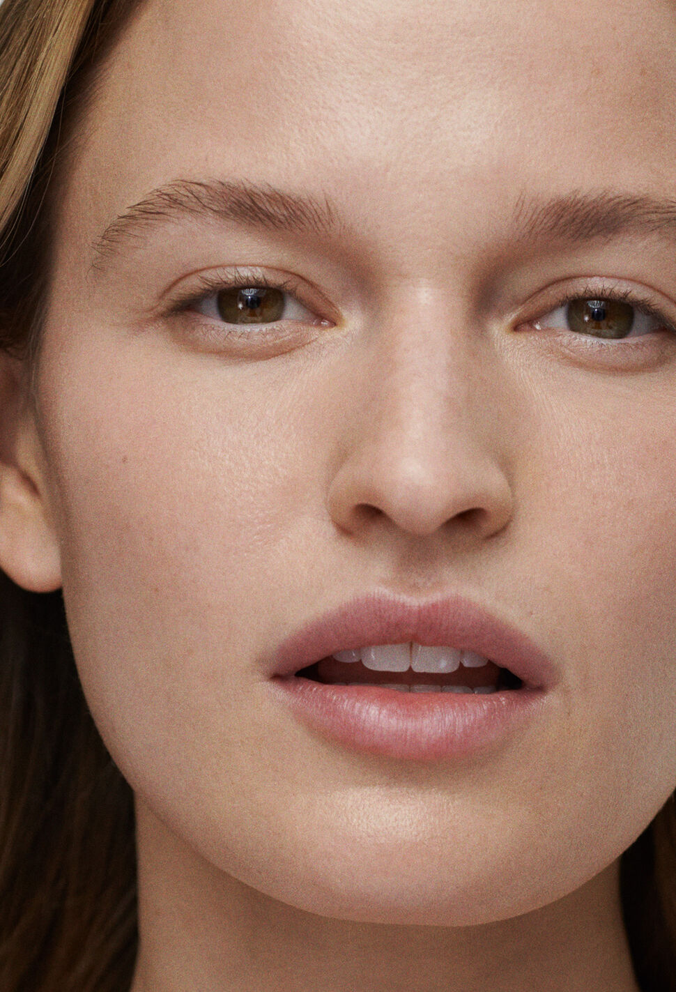 Woman with lips slightly parted with hair tucked behind one ear