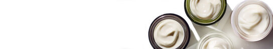 A bird's eye view of four opened fresh moisturizer containers on a white background