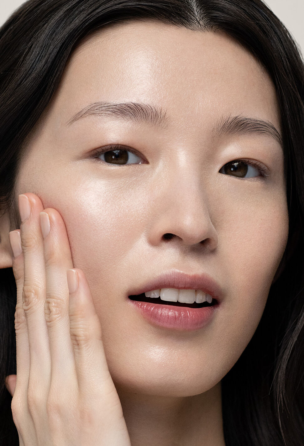 Model with black hair applying product to her cheek with her fingers