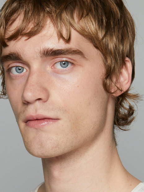 Male model with blue-green eyes against grey background