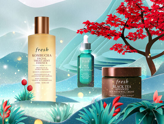 A hand holds Soy Face Cleanser over a blue fresh gift box filled with Kombucha Essence and Tea Elixir