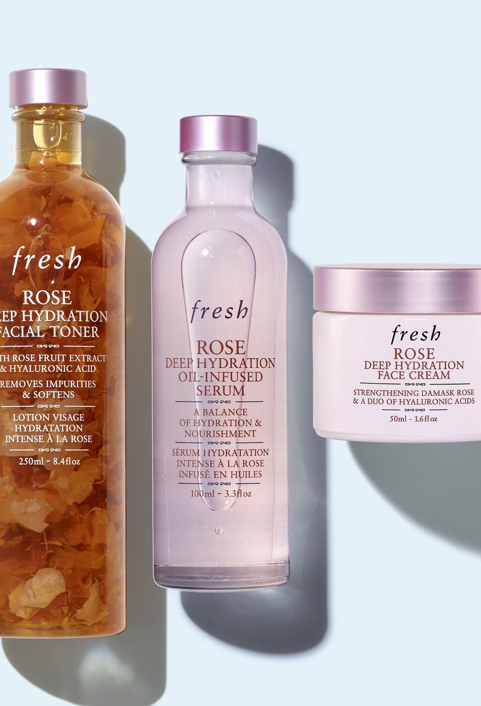 Lineup of Fresh Rose Toner, Serum and Face Cream against light blue background