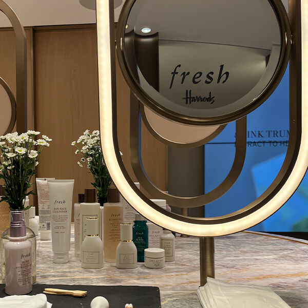 A woman examining a Fresh product in front of a product stand