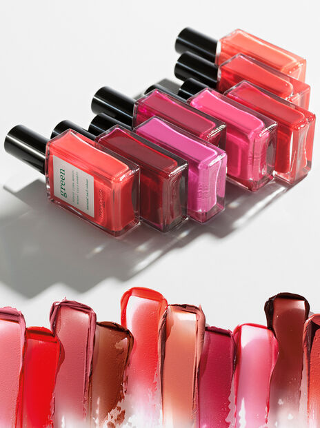 A line of 8 Manucurist nail polish bottles in shades of pink and red lined up on their side