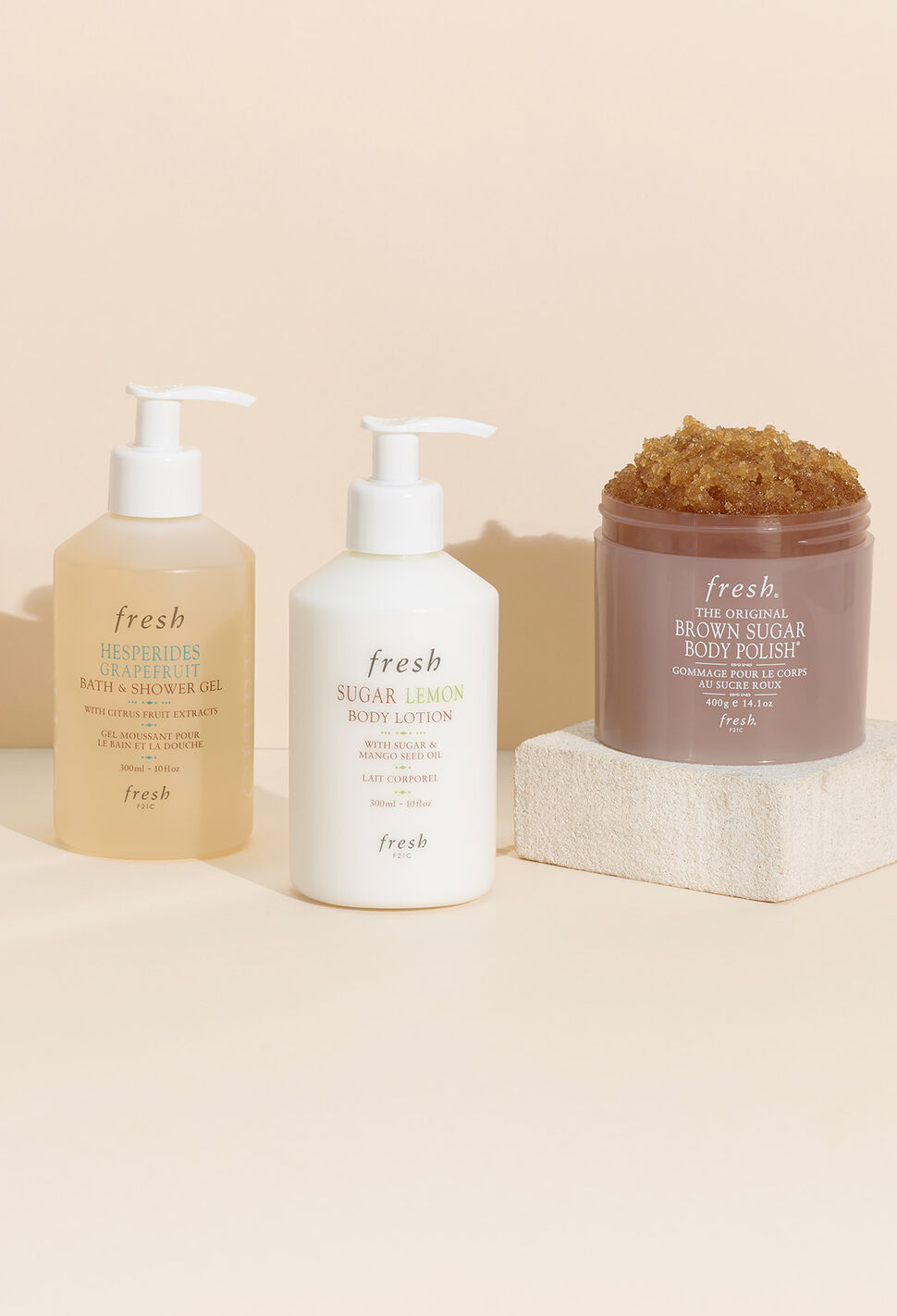 Fresh Body Wash, Lotion and Brown Sugar Body Scrub against a peach colored background