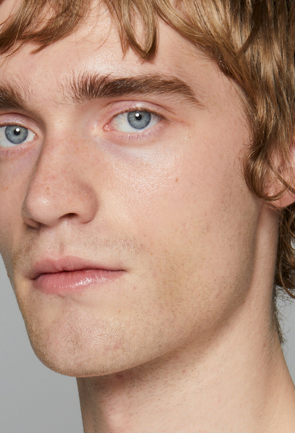Male model with blue-green eyes against grey background