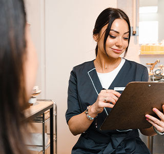 A Fresh employee in a navy top reviews a brown clipboard